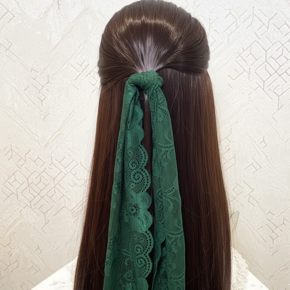 Long brown hair with a green lace ribbon tied in a bow against a white textured background