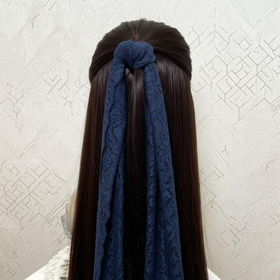 Long dark hair with a blue lace hair accessory against a textured white wall.