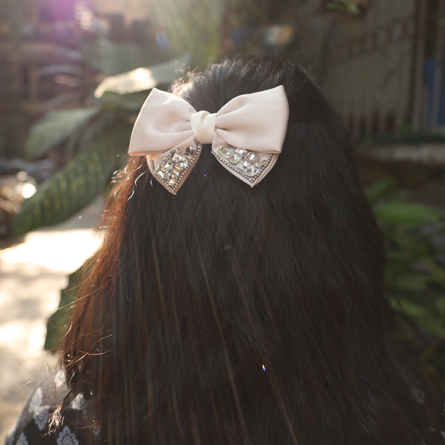 Studded Elegant Satin Bow Clips in soft pink worn on long dark hair under natural sunlight
