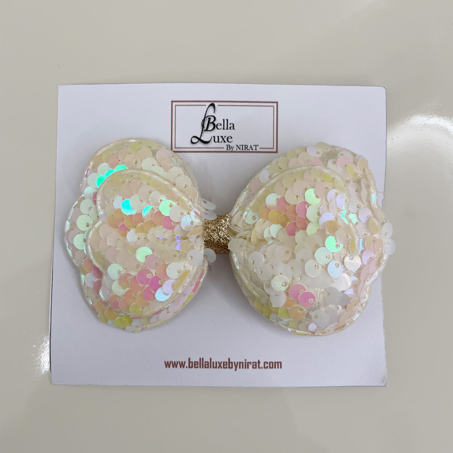 Vibrant Sequined Bow Clips in iridescent white with gold center on Bella Luxe card