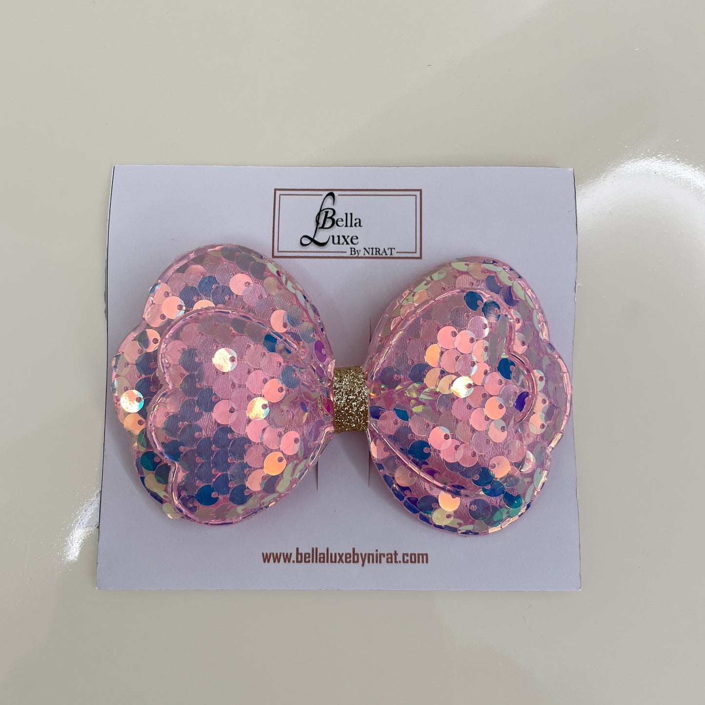 Vibrant Sequined Bow Clips in pink with shimmering round sequins on a display card
