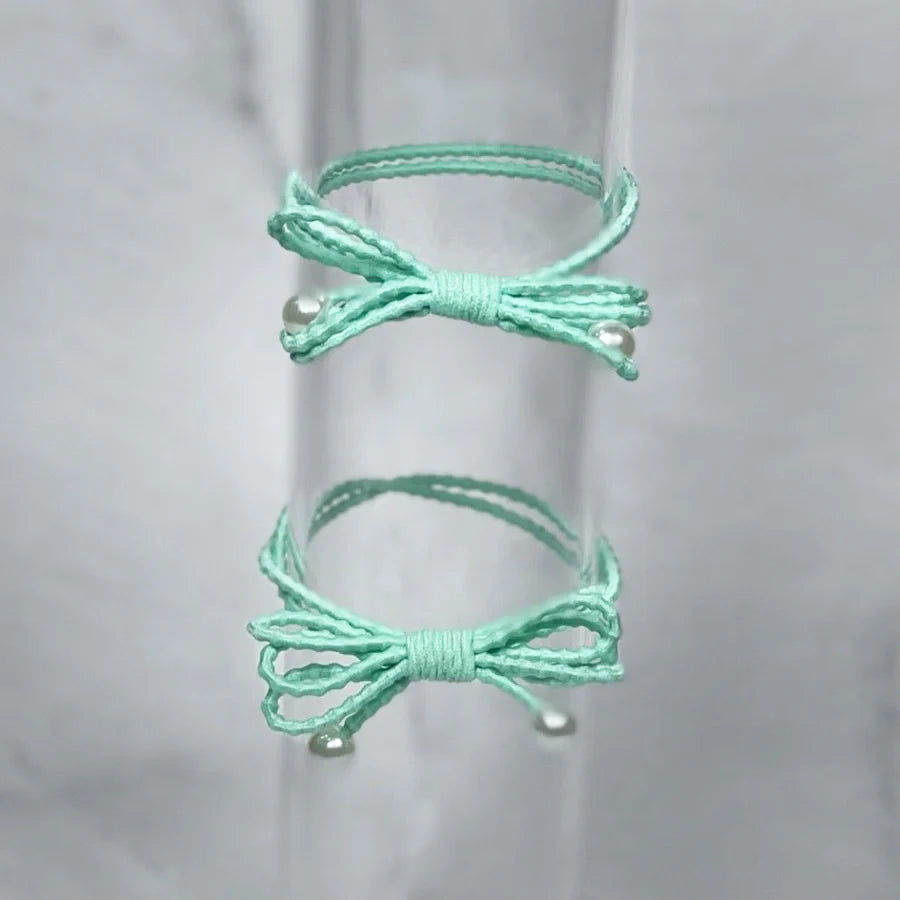 Set of two mint green bow hair ties for women with pearl accents and textured elastic bands