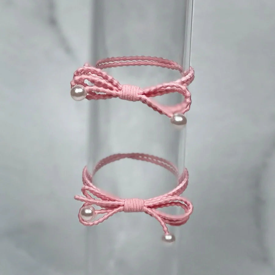 Pink bow hair ties for women with pearl accents on delicate textured elastic bands