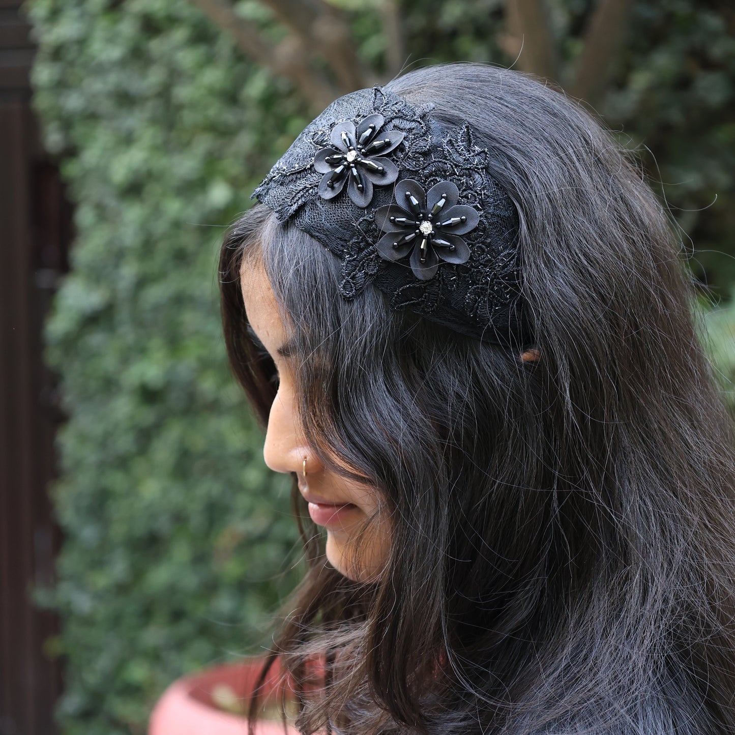 Black broad flower hairbands with floral embellishments worn on dark wavy hair outdoors