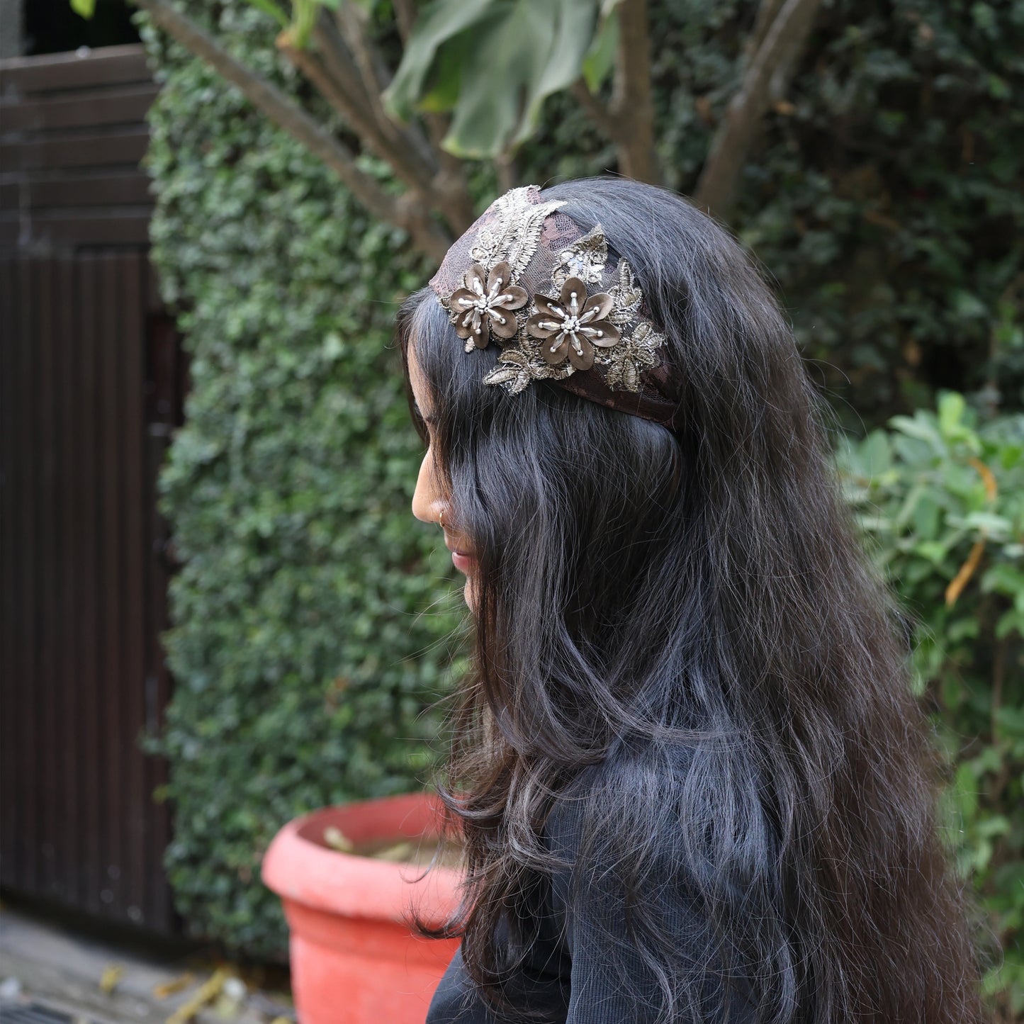 Woman wearing broad flower hairbands with intricate floral design and lace details outdoors