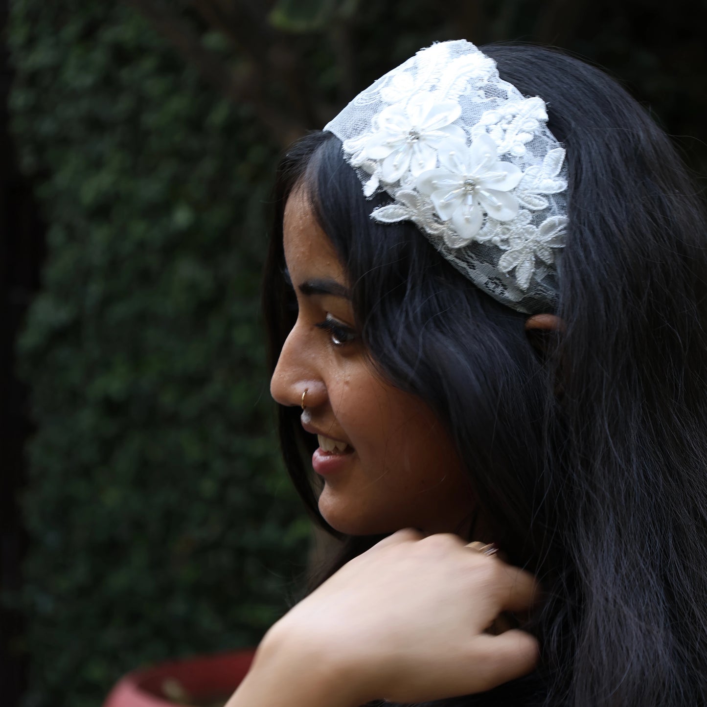 Woman wearing white lace broad flower hairbands with floral detailing in side profile