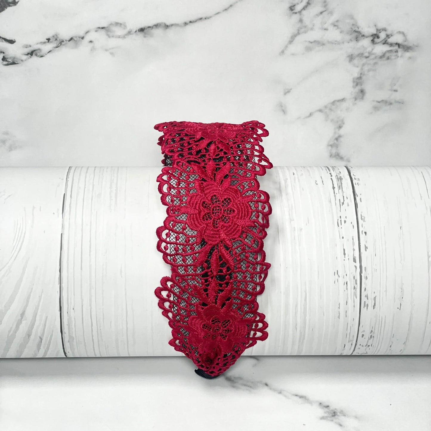 Red floral broad lace hairbands with intricate pattern displayed on white rustic background