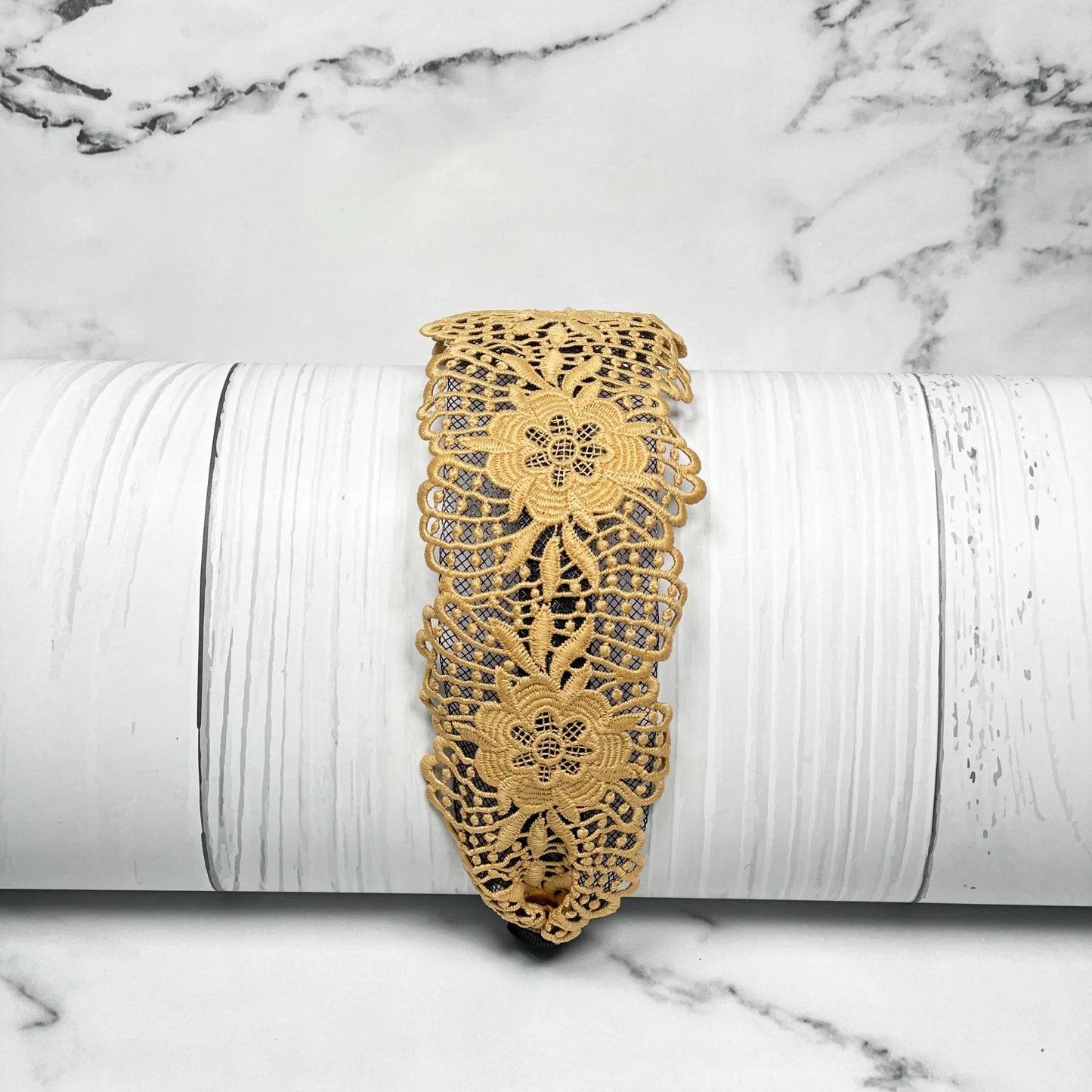 Yellow broad lace hairbands with floral design displayed on white wood background
