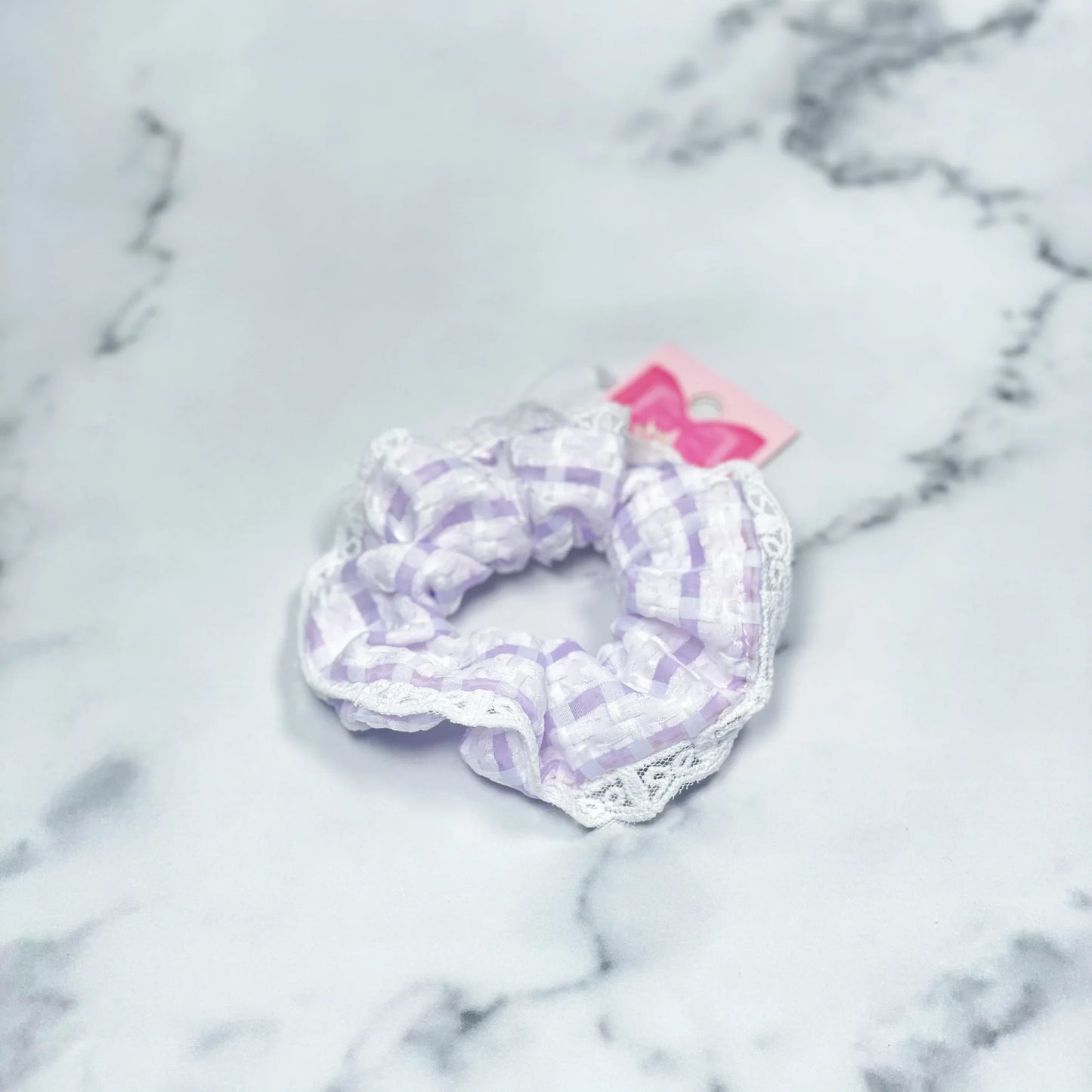 Purple and white check scrunchies with lace detail on marble background