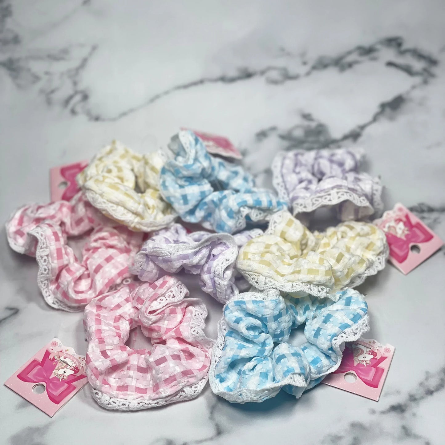 Assorted pastel check scrunchies with lace trim laid out on a marble surface