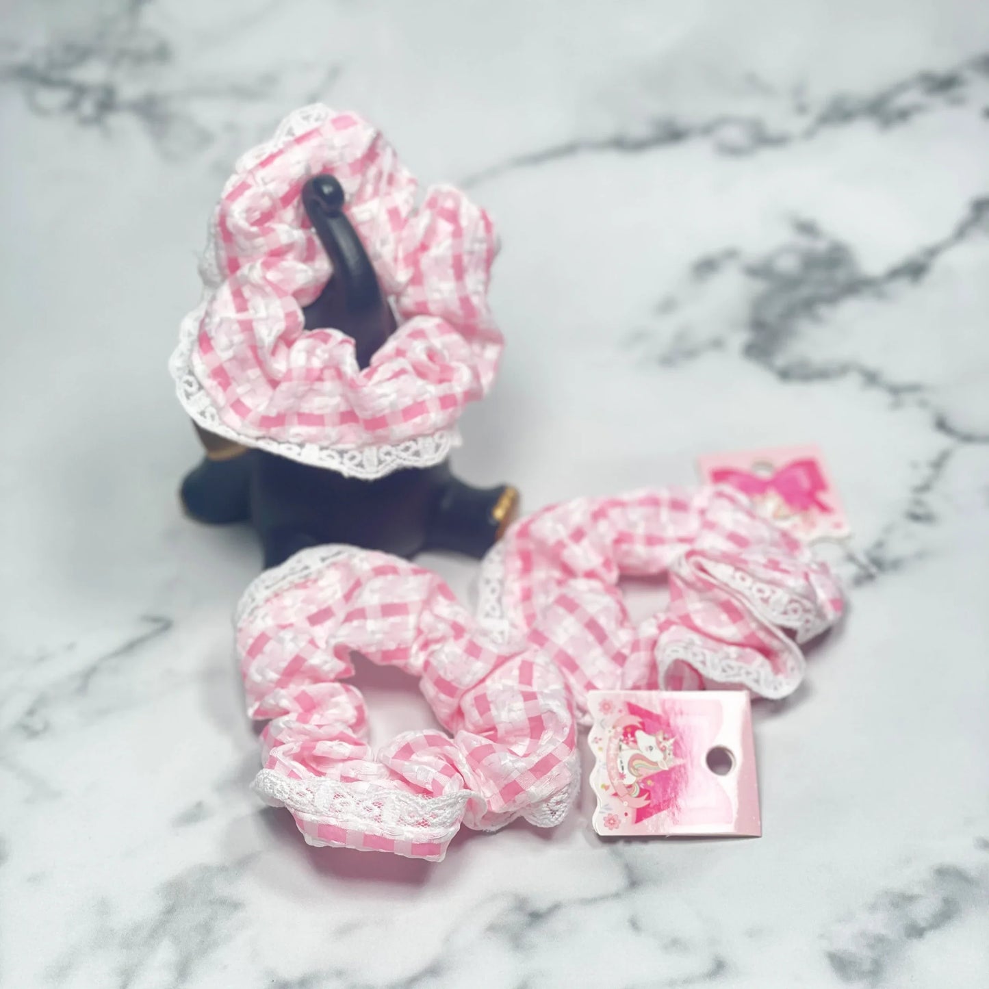 Pink and white check scrunchies with lace trim displayed on marble surface by mydevelopmentstor