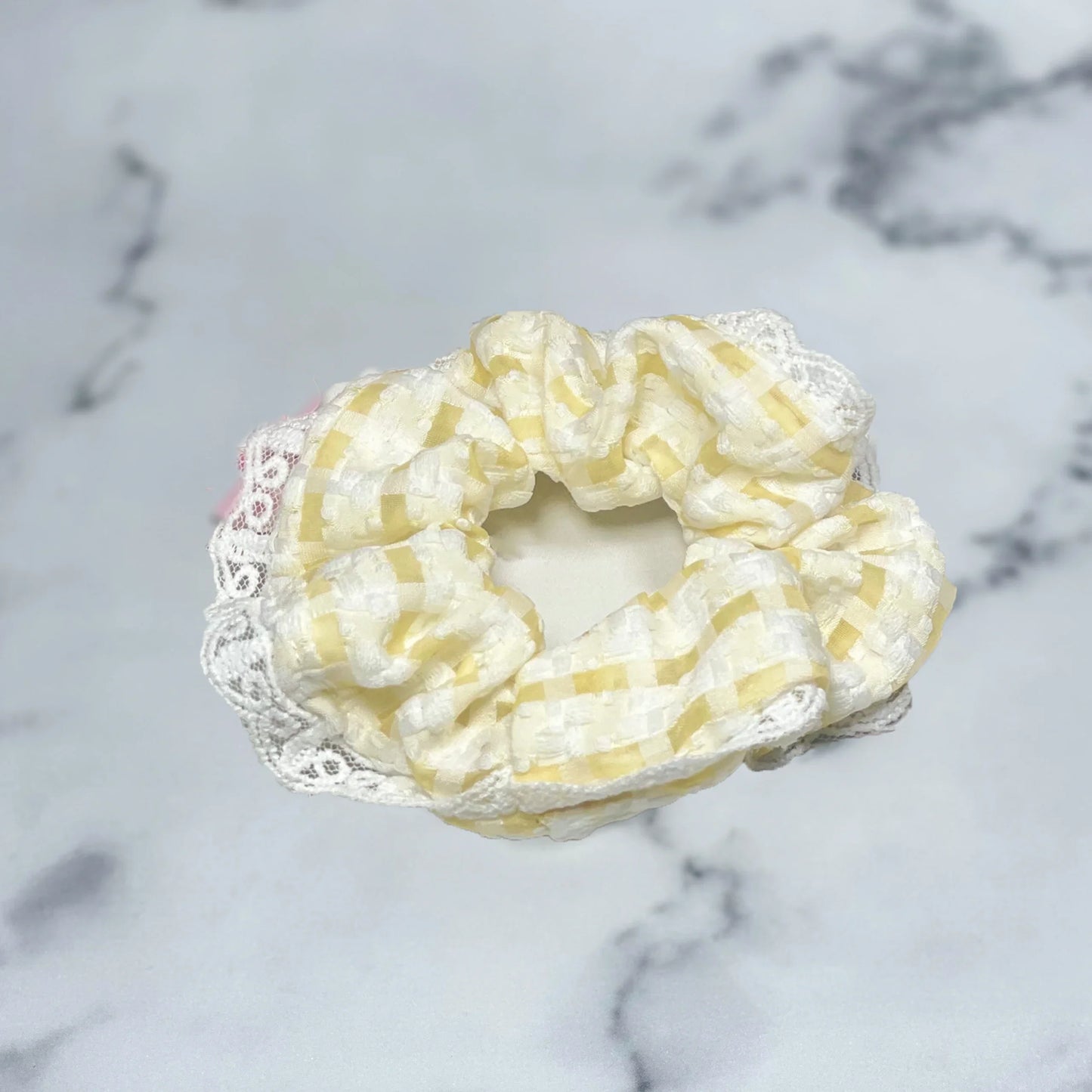Yellow and white check scrunchies with lace edge on marble surface by mydevelopmentstor