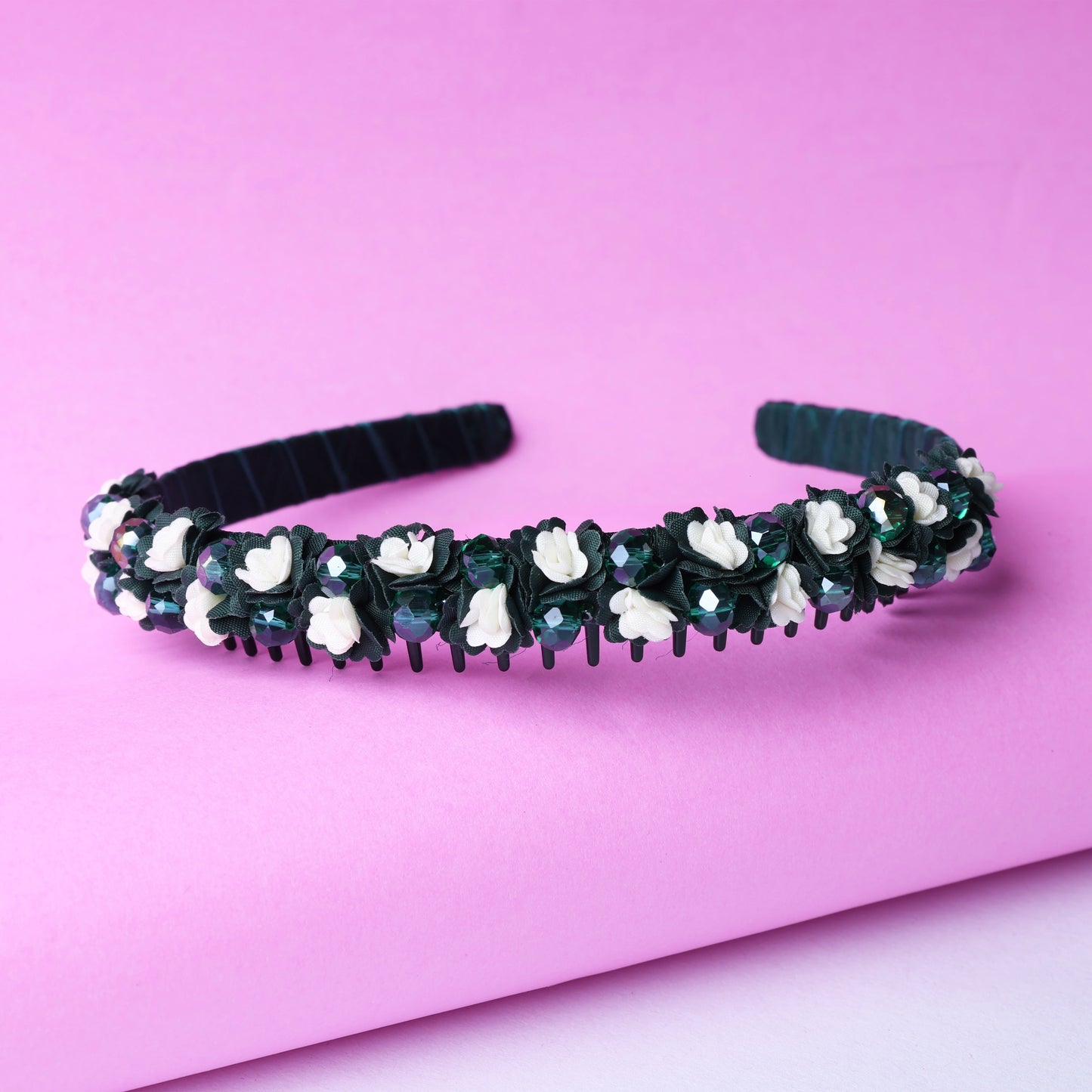 Black crystal flower studded hairbands with white floral accents against a pink background