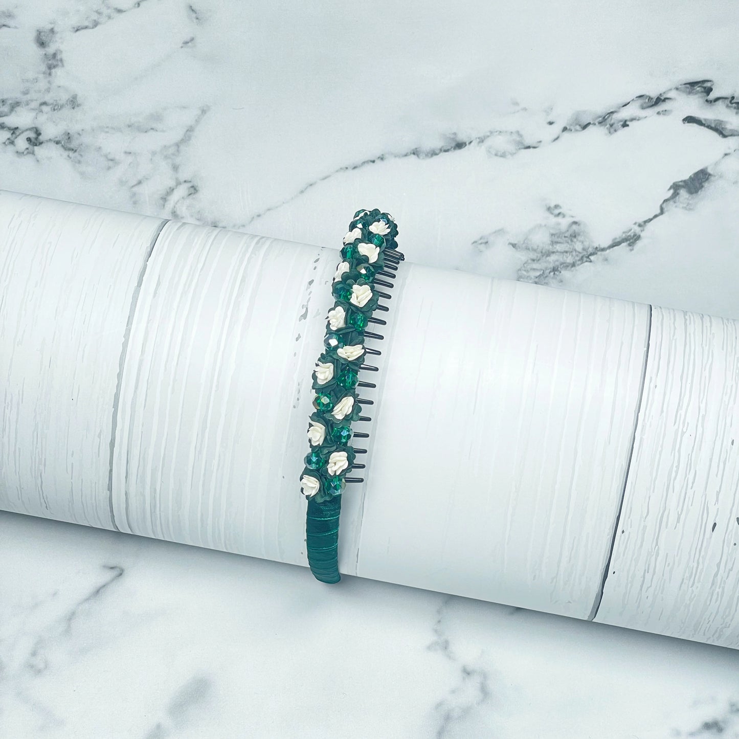 Green crystal flower studded hairbands with white floral embellishments on a textured white surface