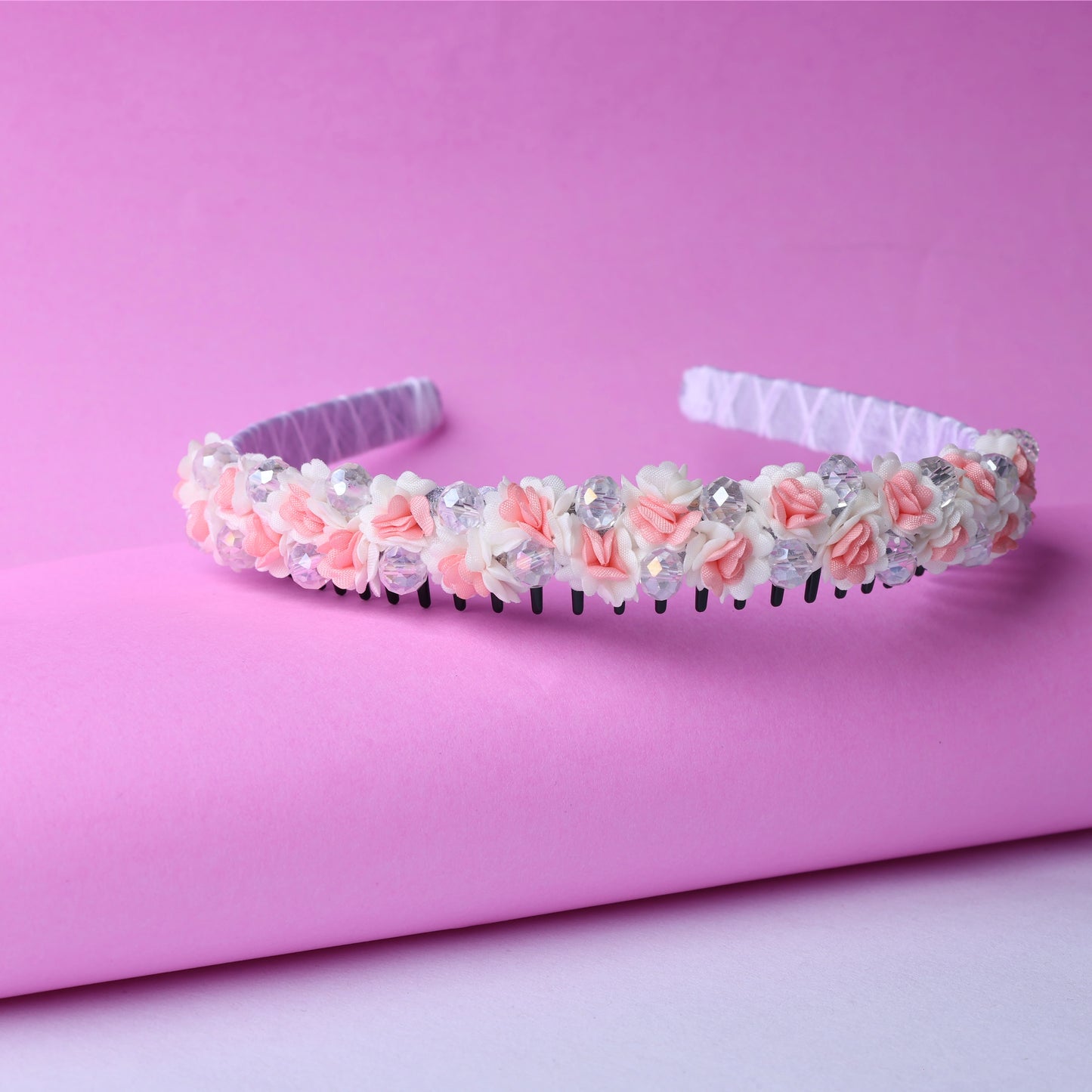 Crystal flower studded hairbands adorned with pink and white fabric flowers and clear crystals on a pink background