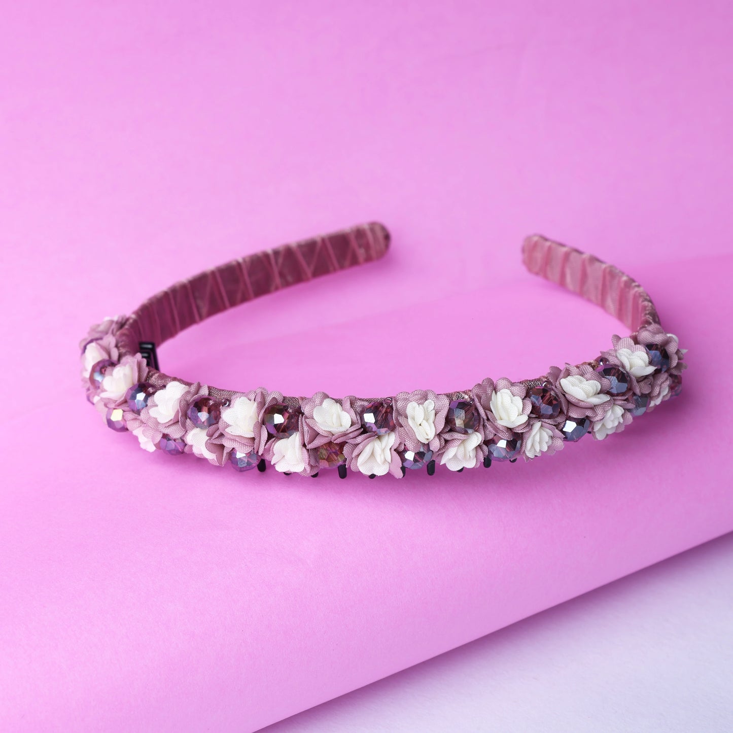 Pink crystal flower studded hairbands decorated with small white flowers on a soft pink background