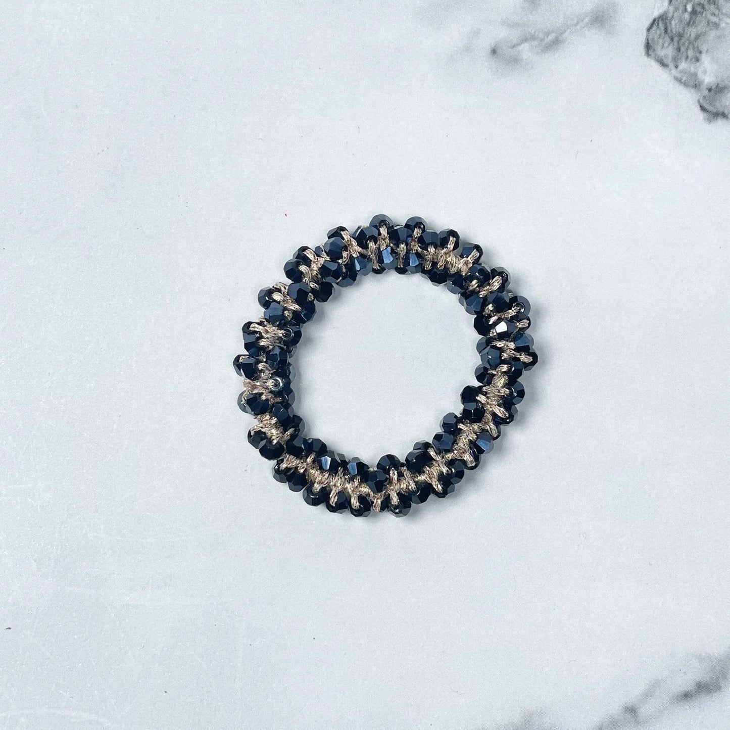 Black crystal studded hair ties with gold accents on white marble background