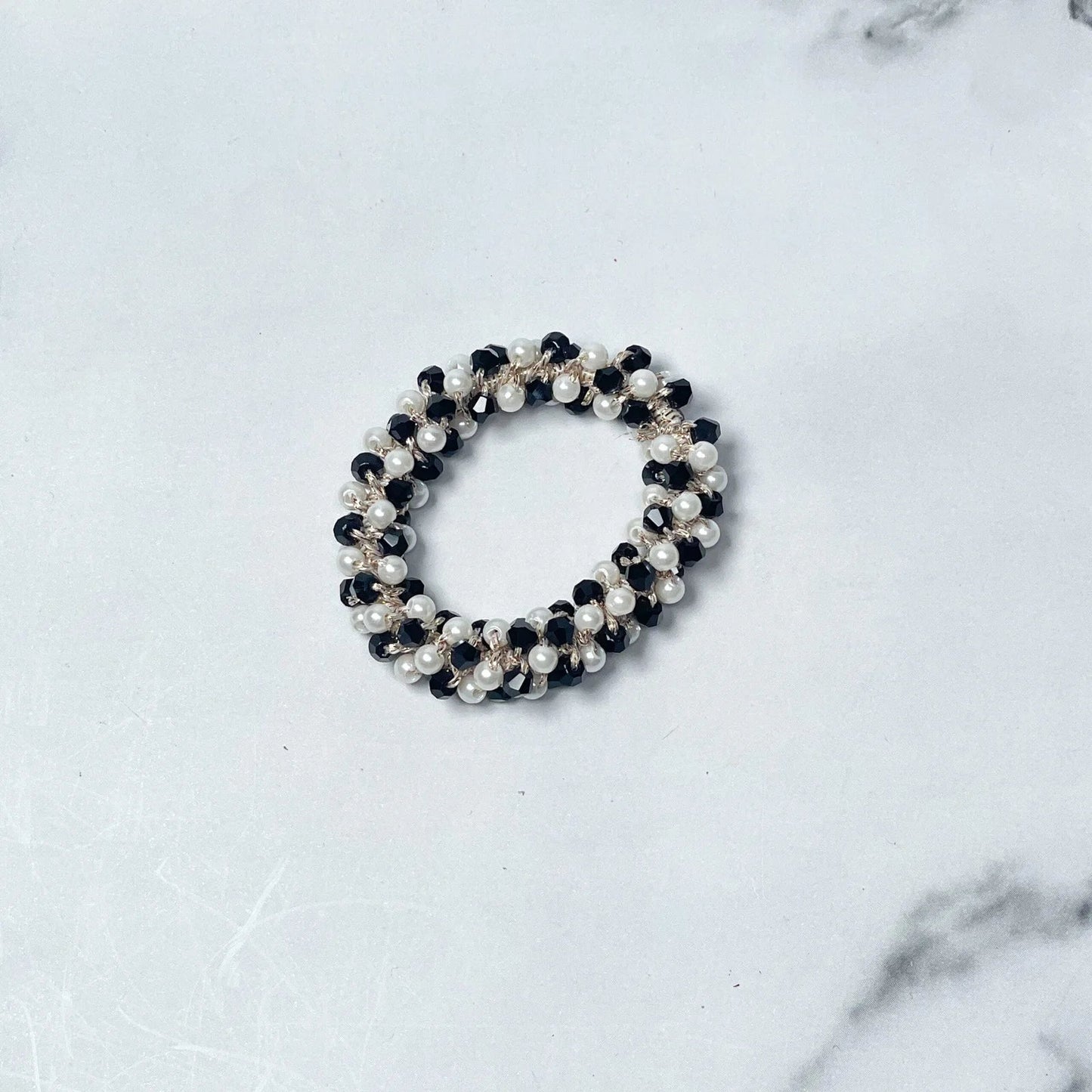 Black and white crystal studded hair ties featuring pearl and bead embellishments on white marble background