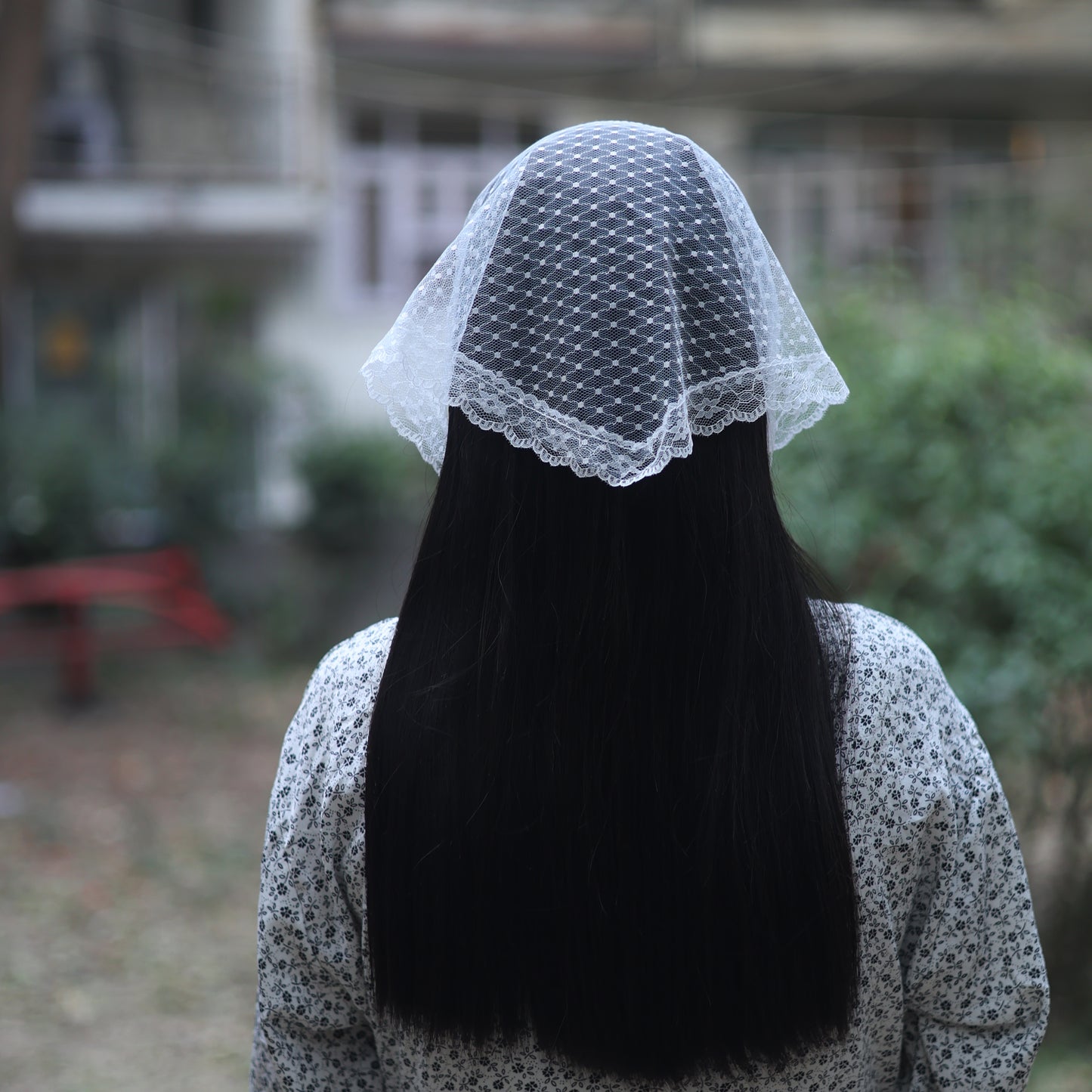 Dotted white lacy bandana worn on the back of the head over long black hair with floral dress