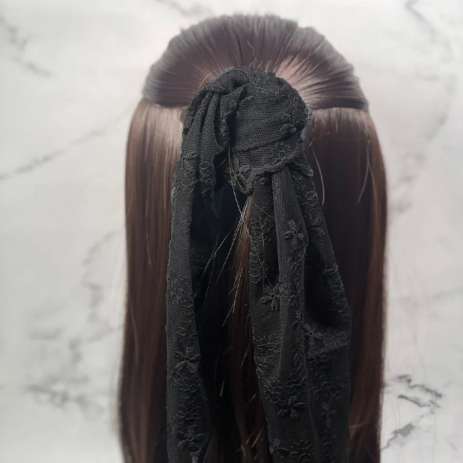 Black embroidered lacy scarf tied as a hair accessory on long brown hair
