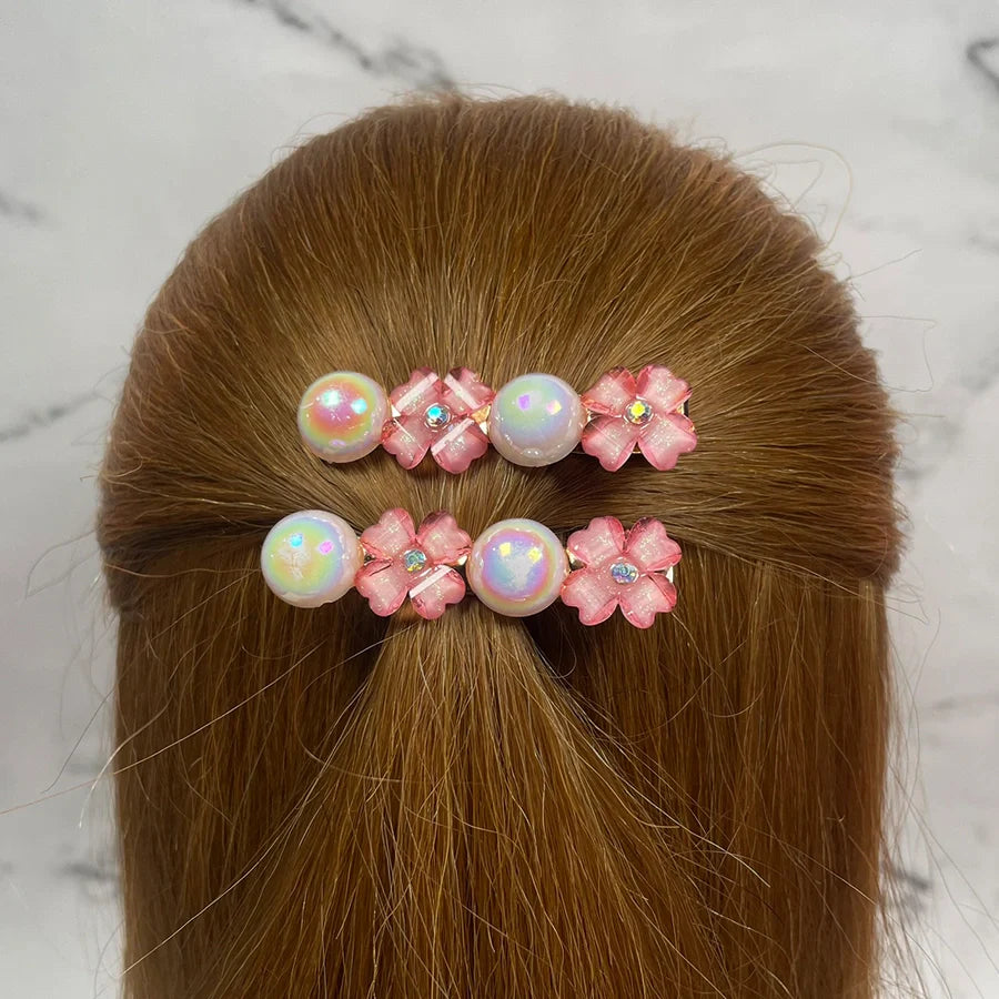 Fancy pearl flower hair pins in pink with shiny pearls and floral accents worn in brown hair