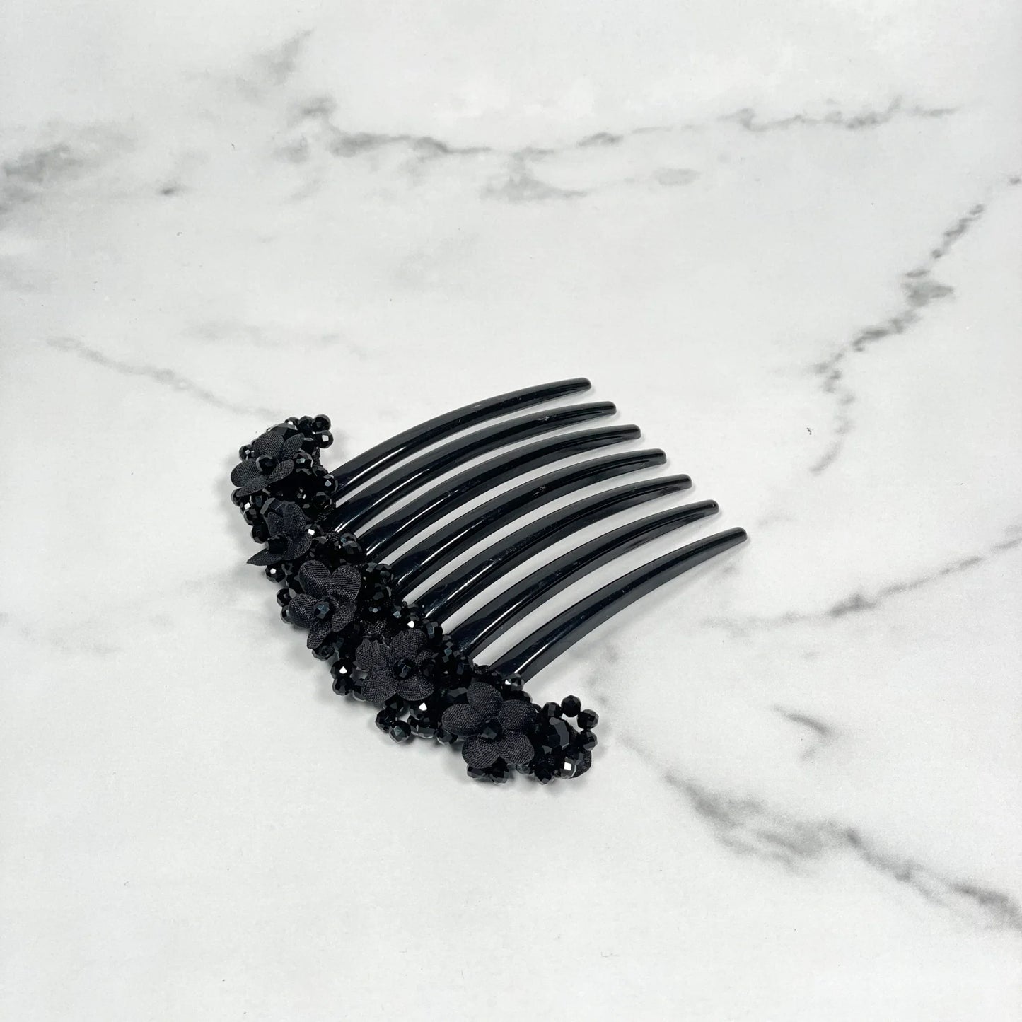 Black floral beaded hair comb clips featuring delicate flower designs on a marble background