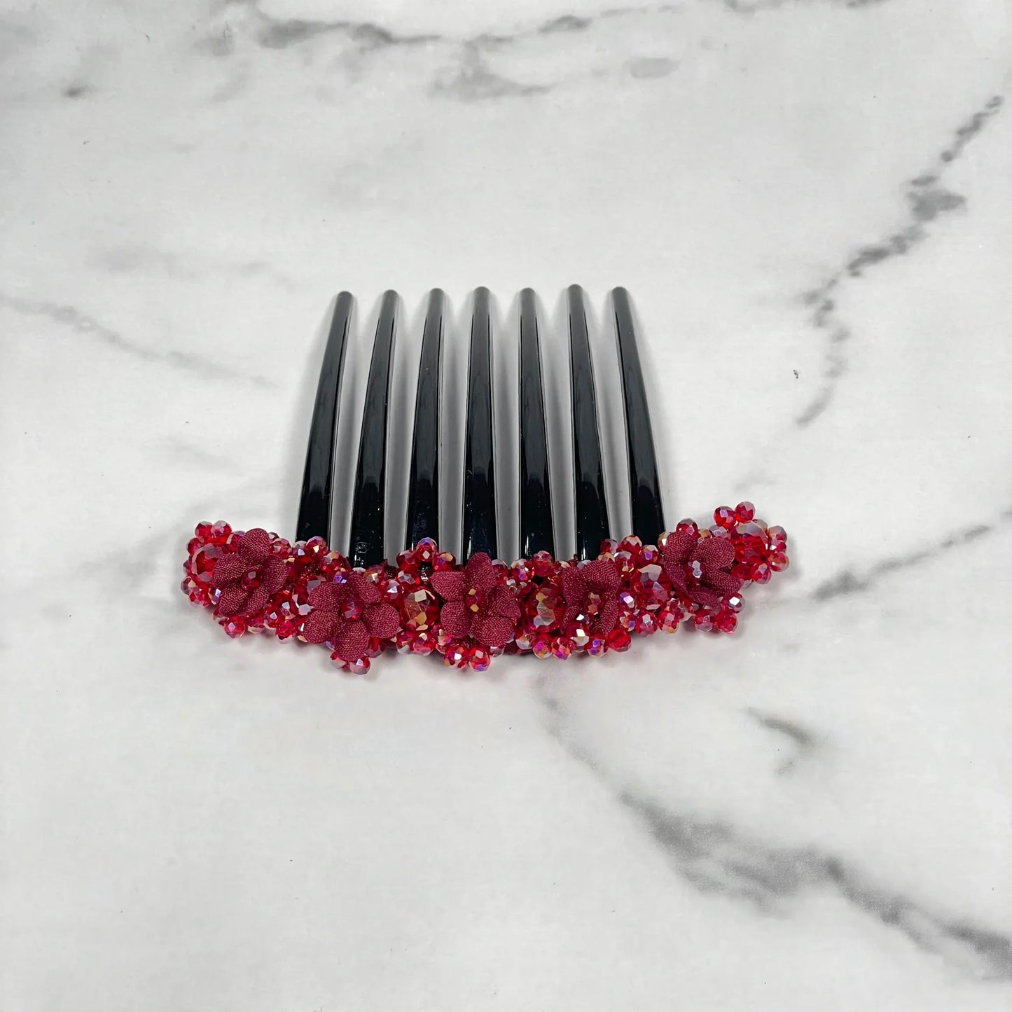 Black hair comb with red floral beaded hair comb clips decoration on white marble background