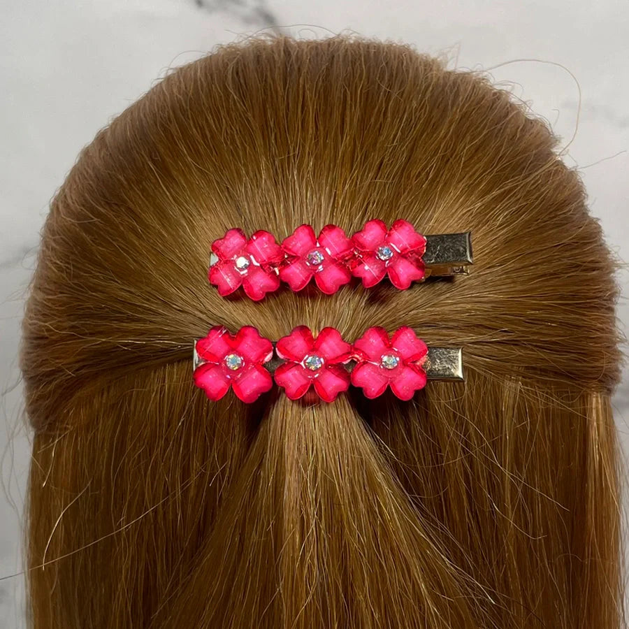Bright pink floral hair pins for women with rhinestone centers clipped in blonde hair