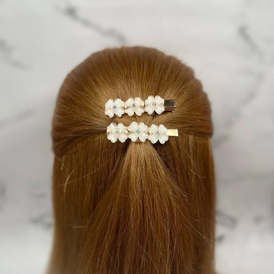 Two floral hair pins for women with white flowers and small decorative gems in brown hair