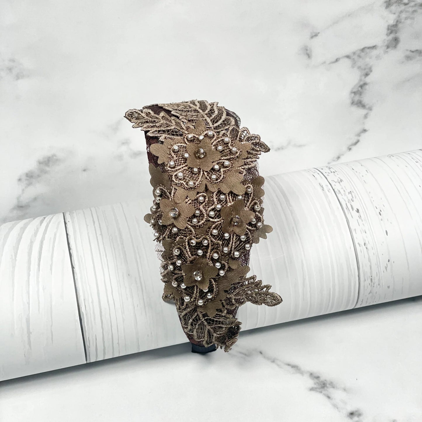 Brown floral lacy hairbands with cutwork and pearl accents on a white textured background