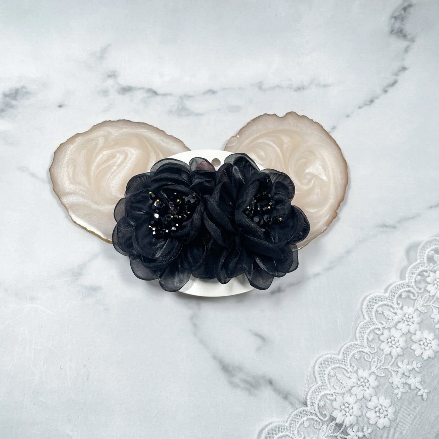 Black floral organza hair pins with delicate bead details on a white background with lace