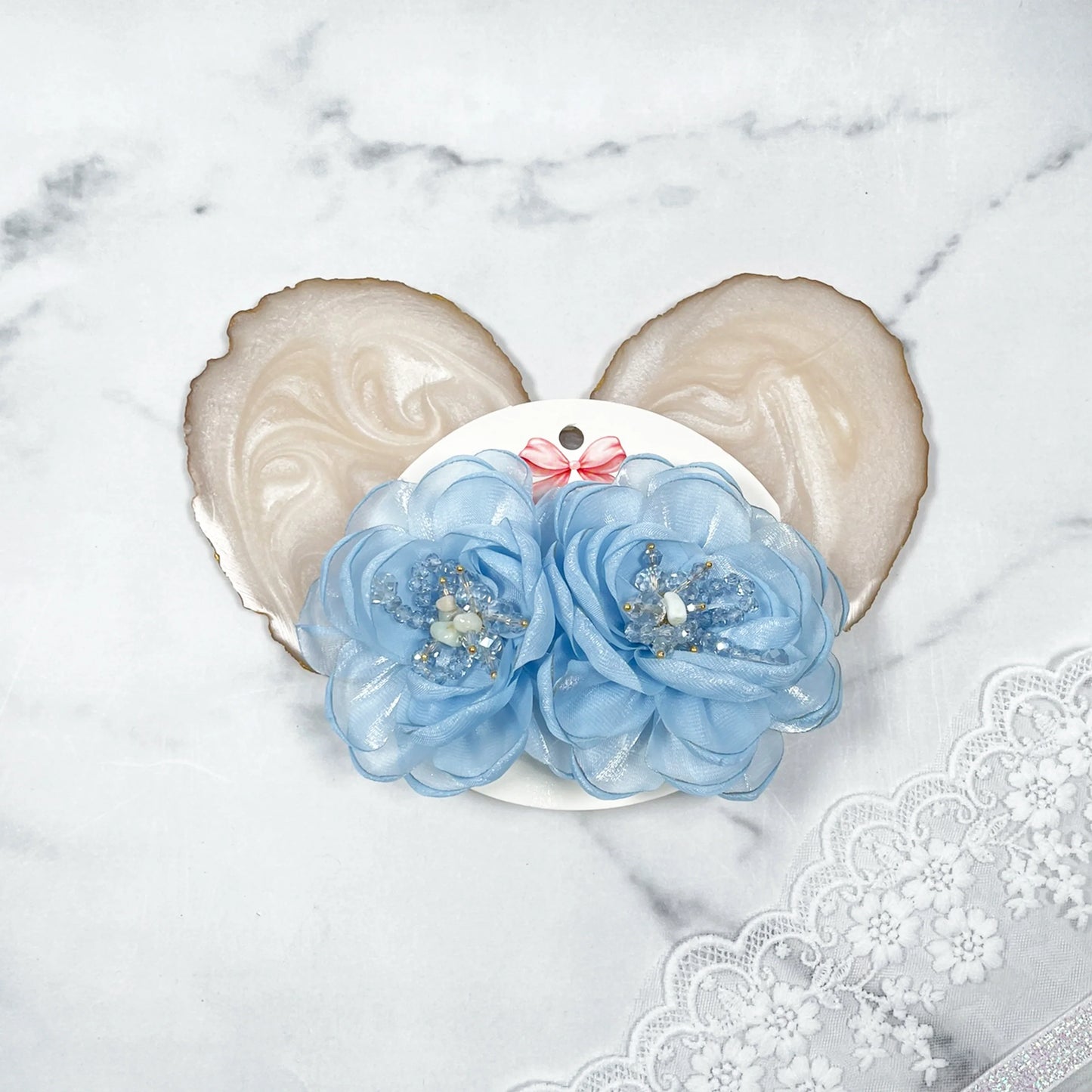 Blue floral organza hair pins with bead accents on decorative card and marble background