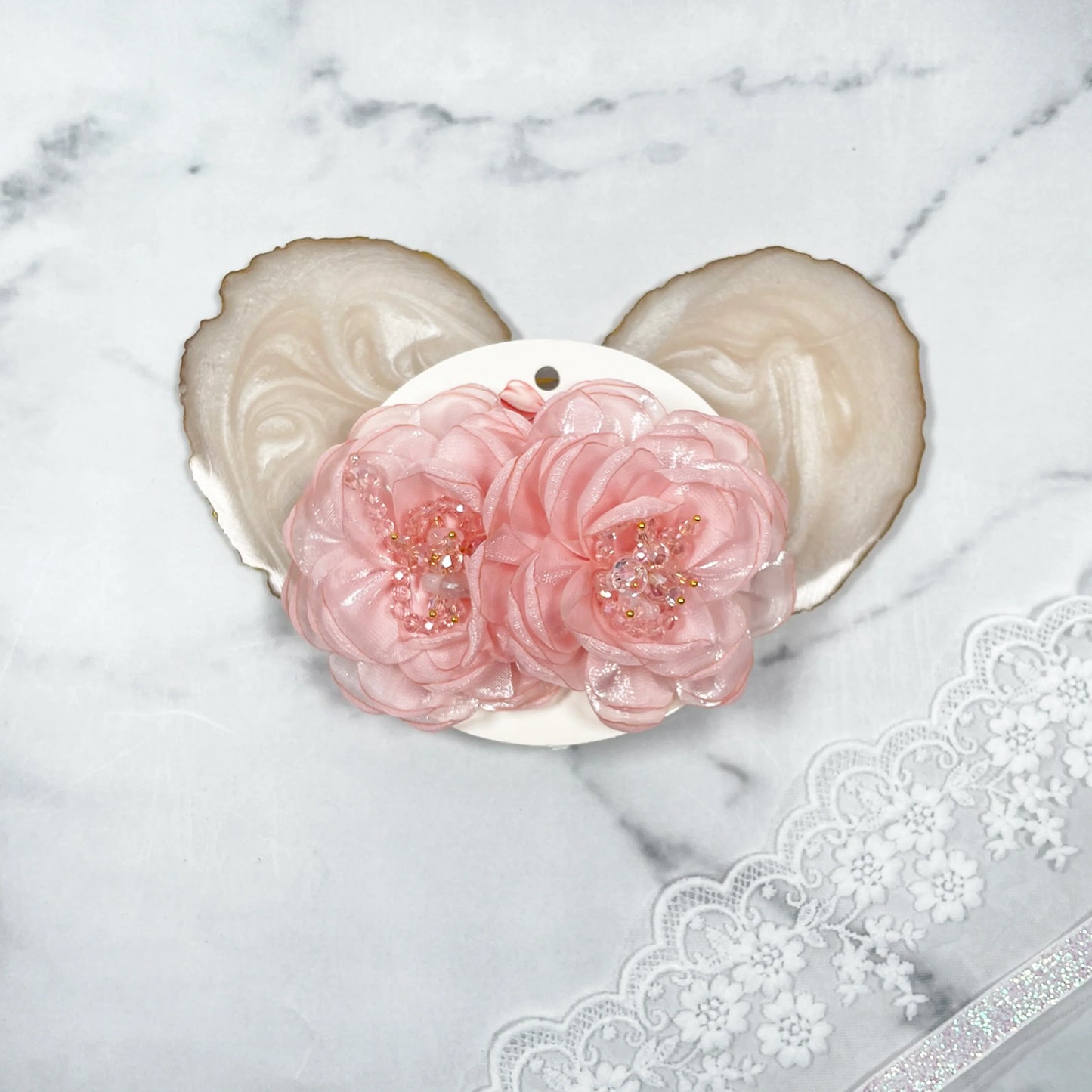 Pink floral organza hair pins with beaded centers on a white display card with lace background