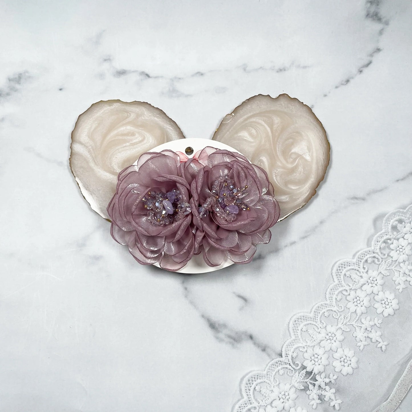Purple floral organza hair pins with delicate bead accents displayed on a white marble surface