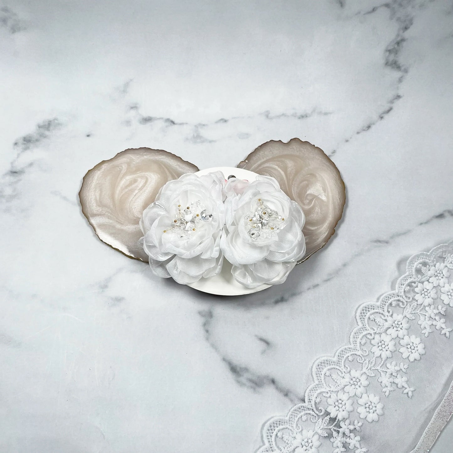 White floral organza hair pins with delicate bead detailing on a marble background with lace fabric