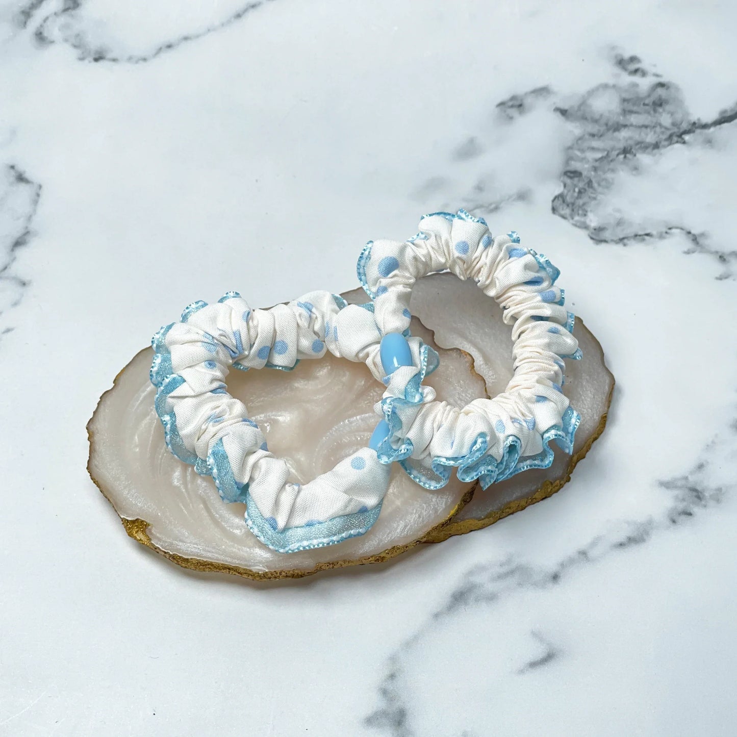White and blue frill polka dot hair ties with ruffled edges displayed on a decorative stone plate