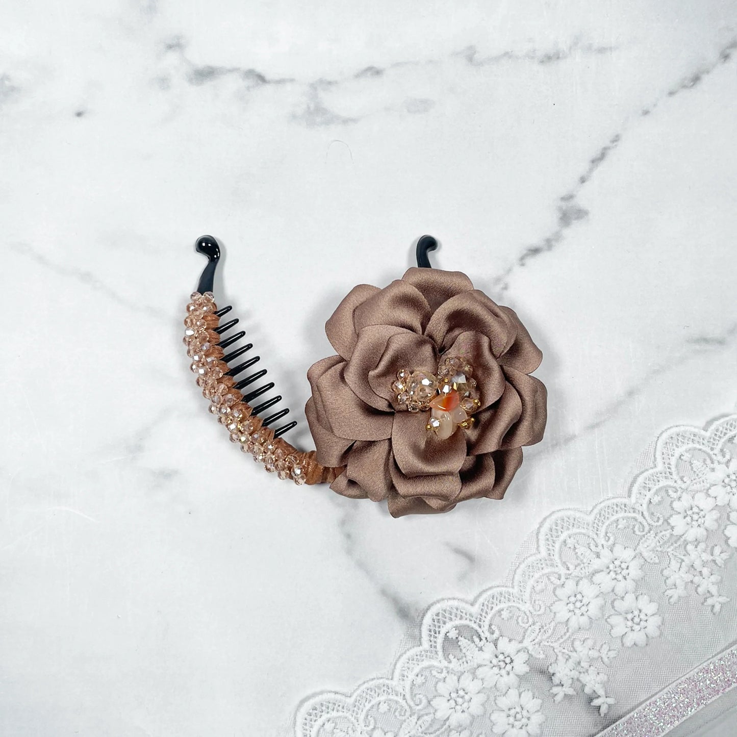 Bella Luxe golden crystal banana clip with brown fabric flower and crystal accents on marble background