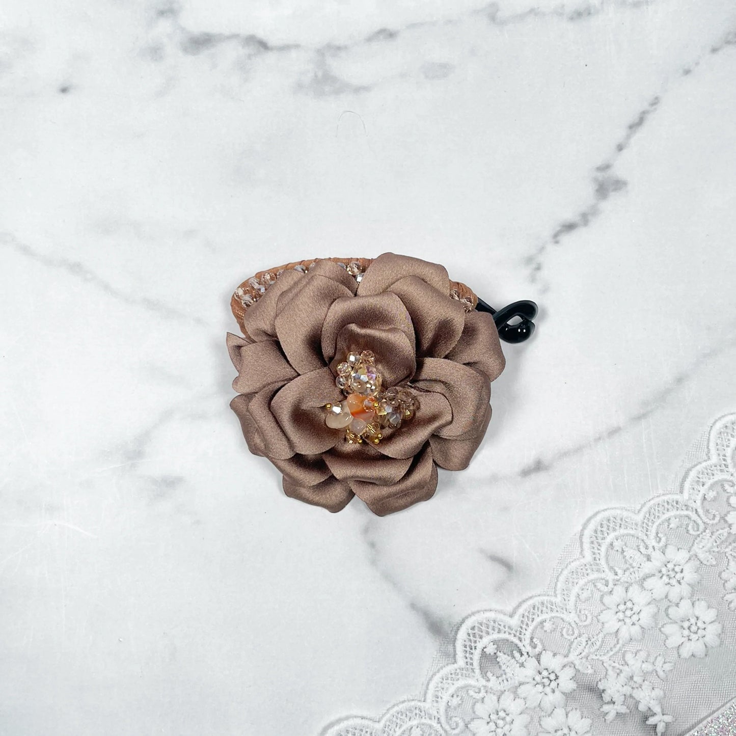 Bella Luxe golden crystal banana clip with decorative brown fabric flower on marble background