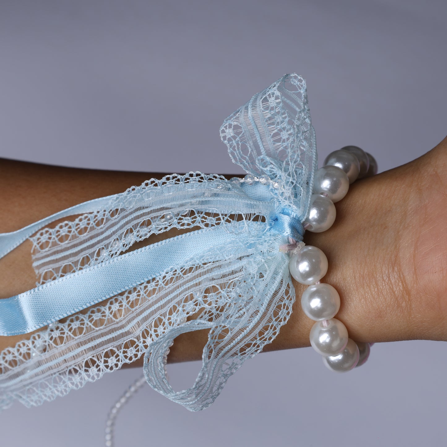 Light blue lace satin pearl hair ties wrapped around wrist with delicate lace and pearl beads