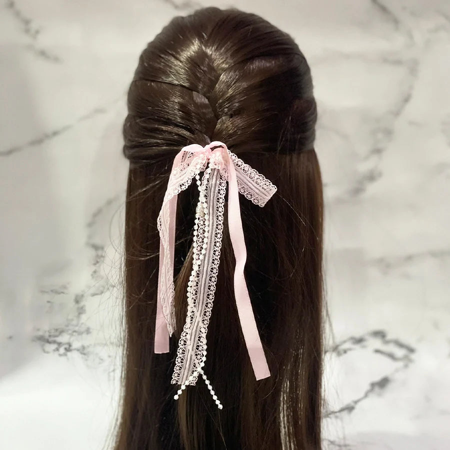 Pink lace satin pearl hair ties styled on long brown hair against a marble background