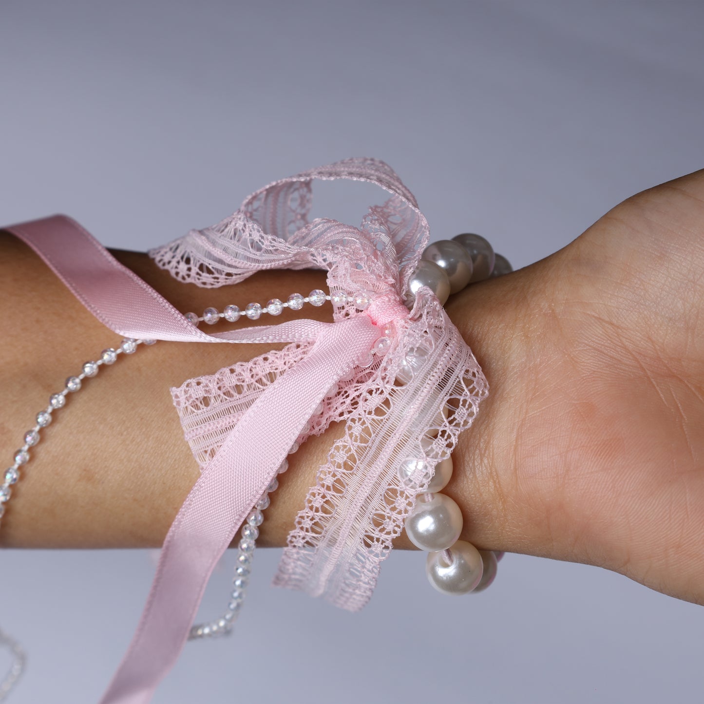 Pink lace satin pearl hair ties wrapped around wrist featuring delicate lace and pearl accents