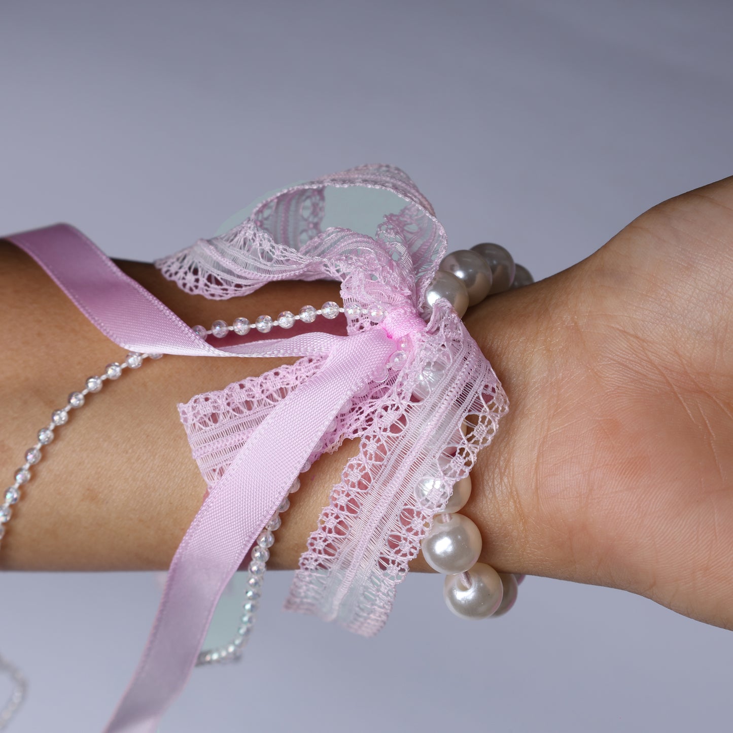 Pink lace satin pearl hair ties wrapped around wrist with delicate ribbon and pearls