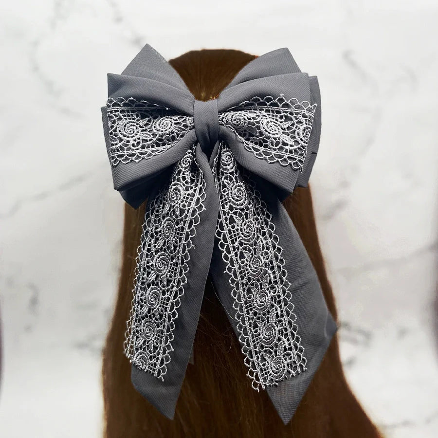 Gray fabric lacy hair bow clip with intricate white lace detailing on long tails