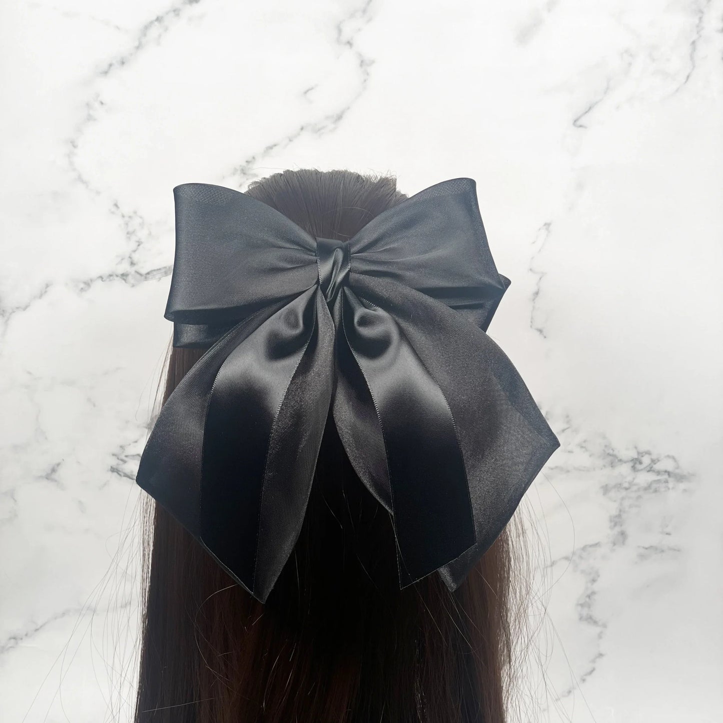 Black Organza and Satin Bow Clips worn on long brown hair against a marble background