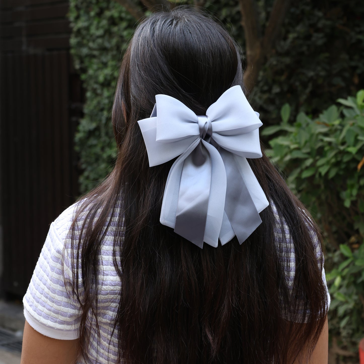 Back view of woman wearing white Organza and Satin Bow Clips in long dark hair outdoors