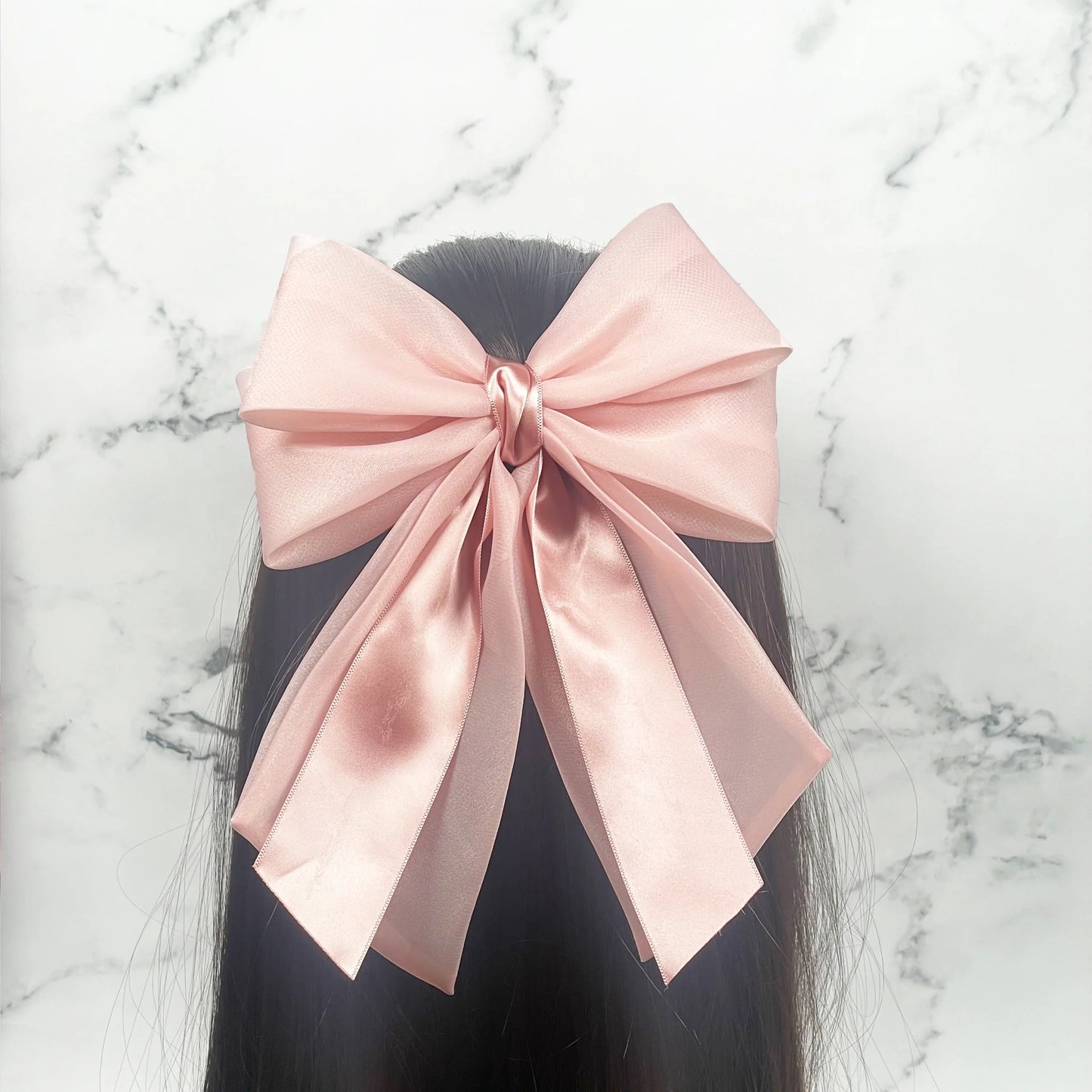 Large pink Organza and Satin Bow Clips worn on long dark hair against marble background