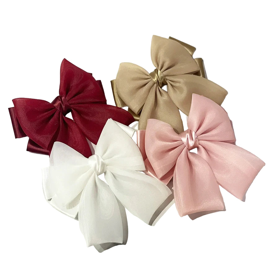 Set of organza satin bow hair clips in burgundy, beige, white, and pink on marble background