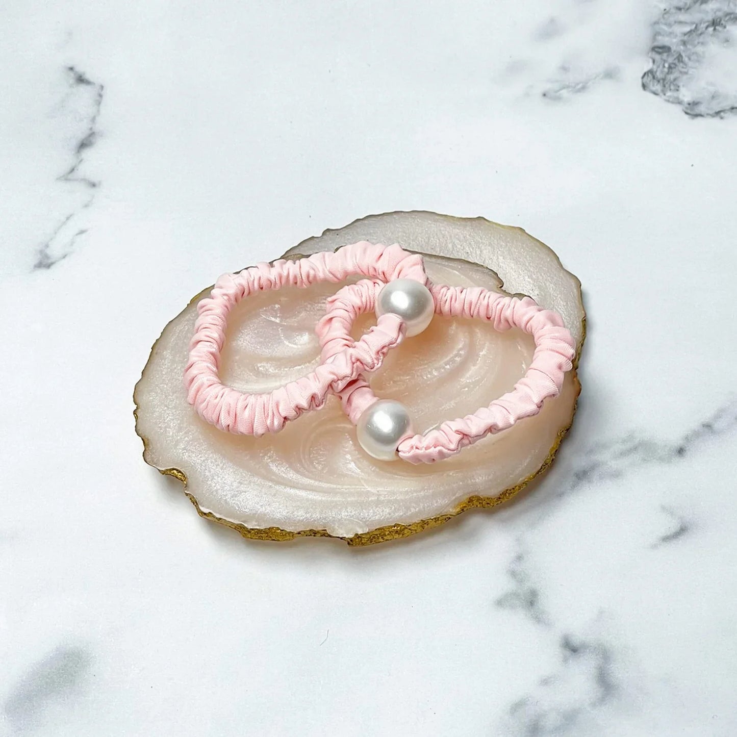 Pastel hair ties with pearl in soft pink color displayed on decorative stone tray