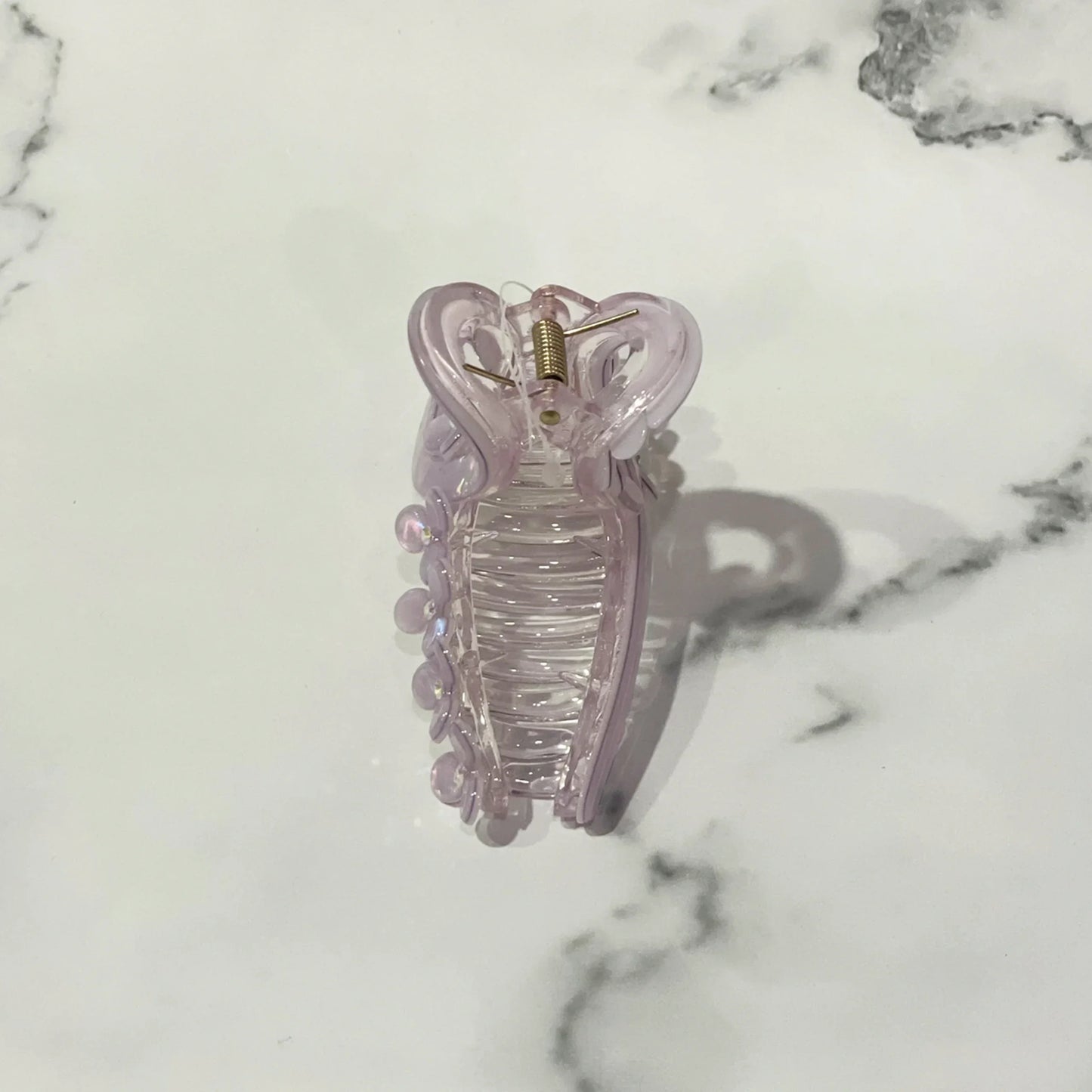 Light purple pearl floral hair clutches with a spring clasp on a white marble surface