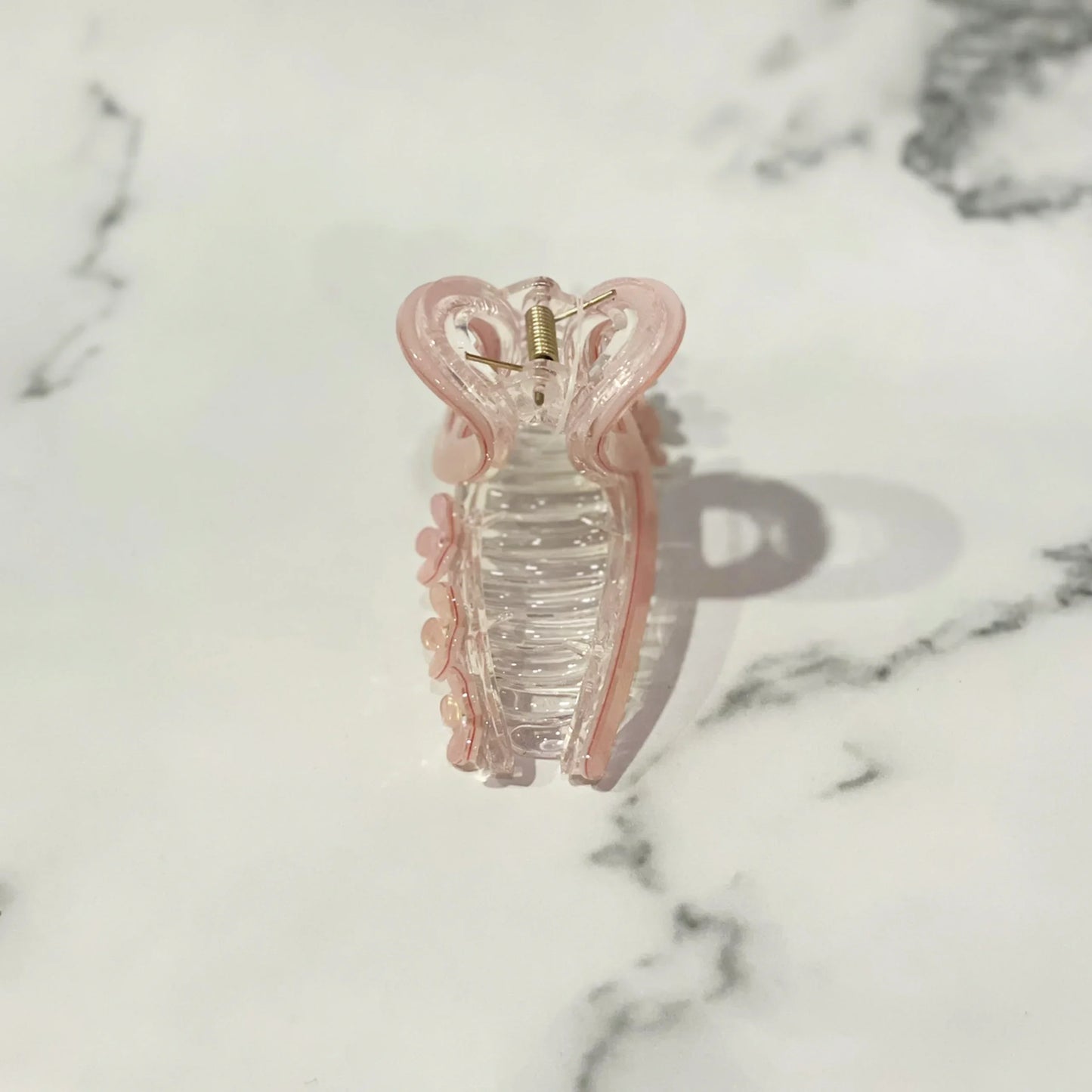 Pink translucent pearl floral hair clutches with a spring clasp on a marble background